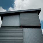 Low angle view of a sleek, modern metal building in Alkmaar with a vibrant blue, cloud-filled sky.